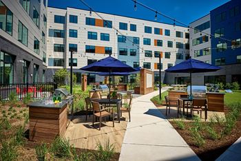 An outdoor patio with tables and umbrellas in front of an apartment building